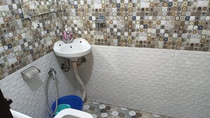 Kylpyhuoneessa on valkoinen pesuallas, suihku ja wc. Seinät on laatoitettu kuvioidulla kuviolla.