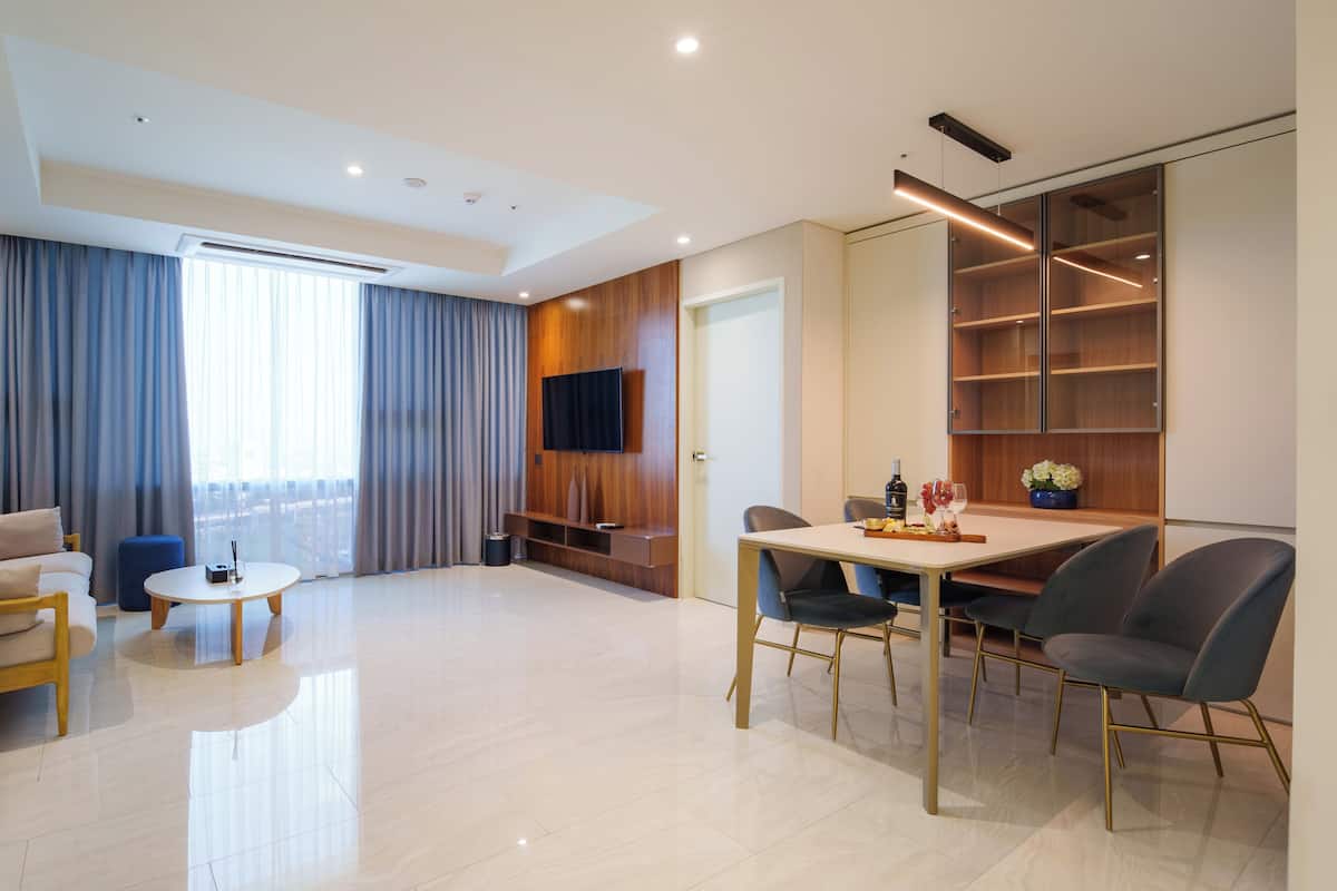 A modern living room with a sofa, a coffee table, a dining table with chairs, and a TV mounted on the wall.