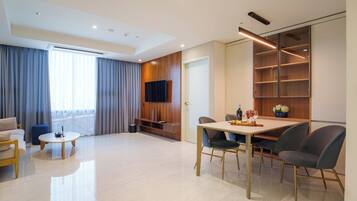 A modern living room with a sofa, a coffee table, a dining table with chairs, and a TV mounted on the wall.