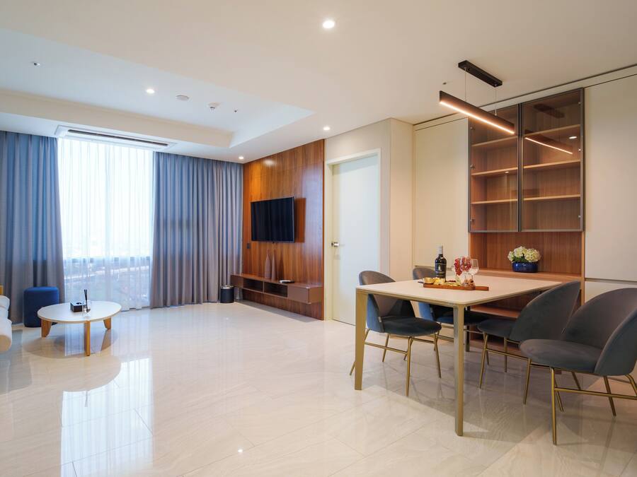 Una sala de estar moderna con un sofá, una mesa de centro, una mesa de comedor con sillas y un televisor montado en la pared.