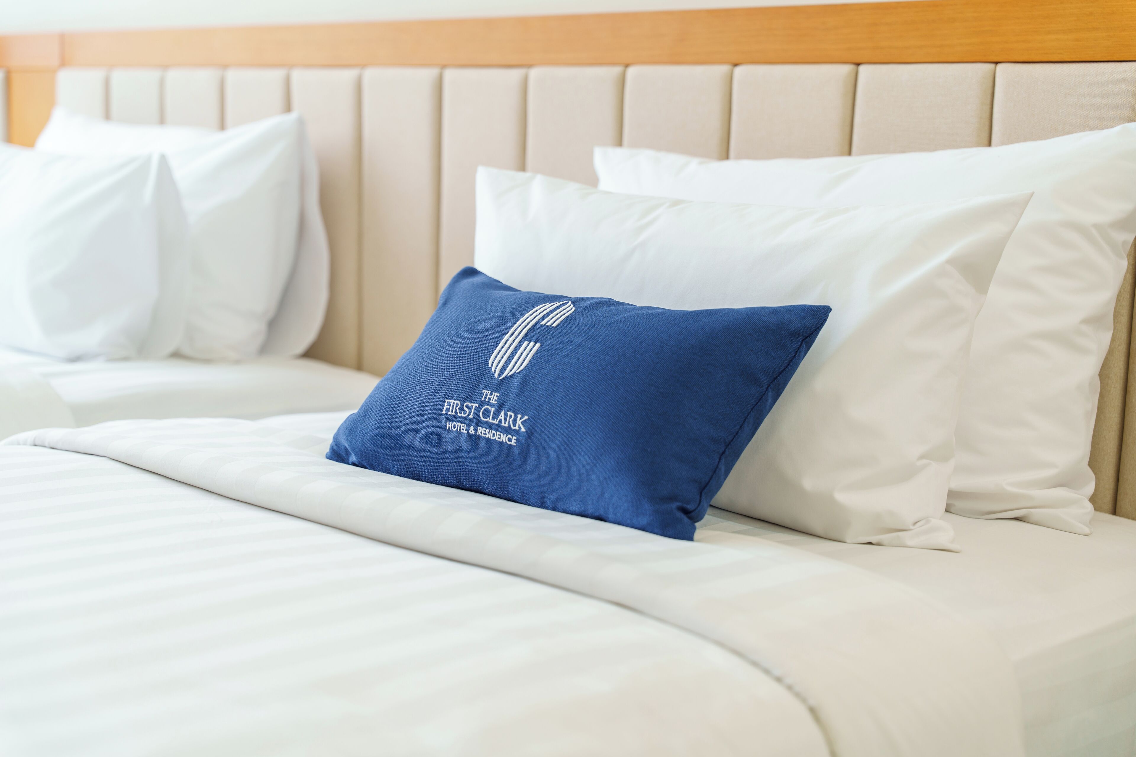 A neatly made bed with white bedding and a blue pillow with text.