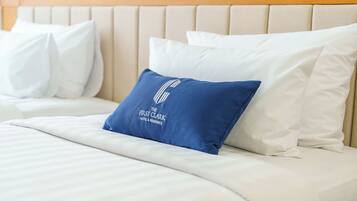 A neatly made bed with white bedding and a blue pillow with text.