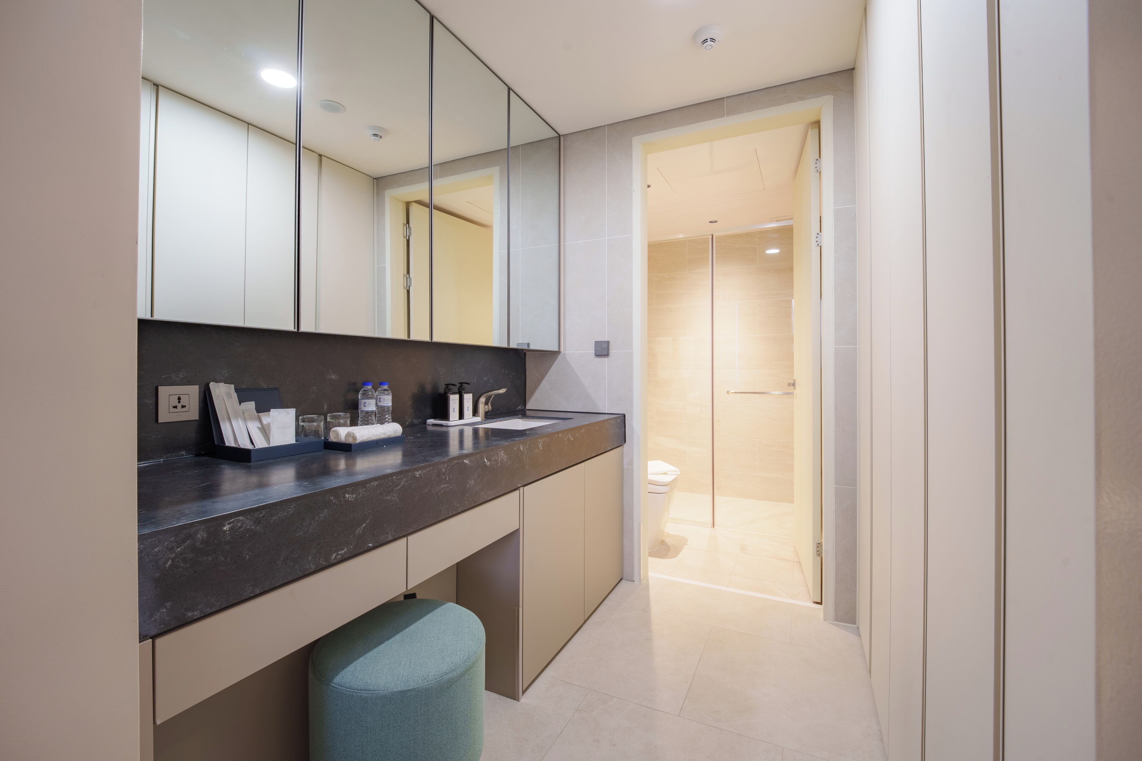A modern bathroom with a dark countertop, a mirror, a sink, and a shower area.