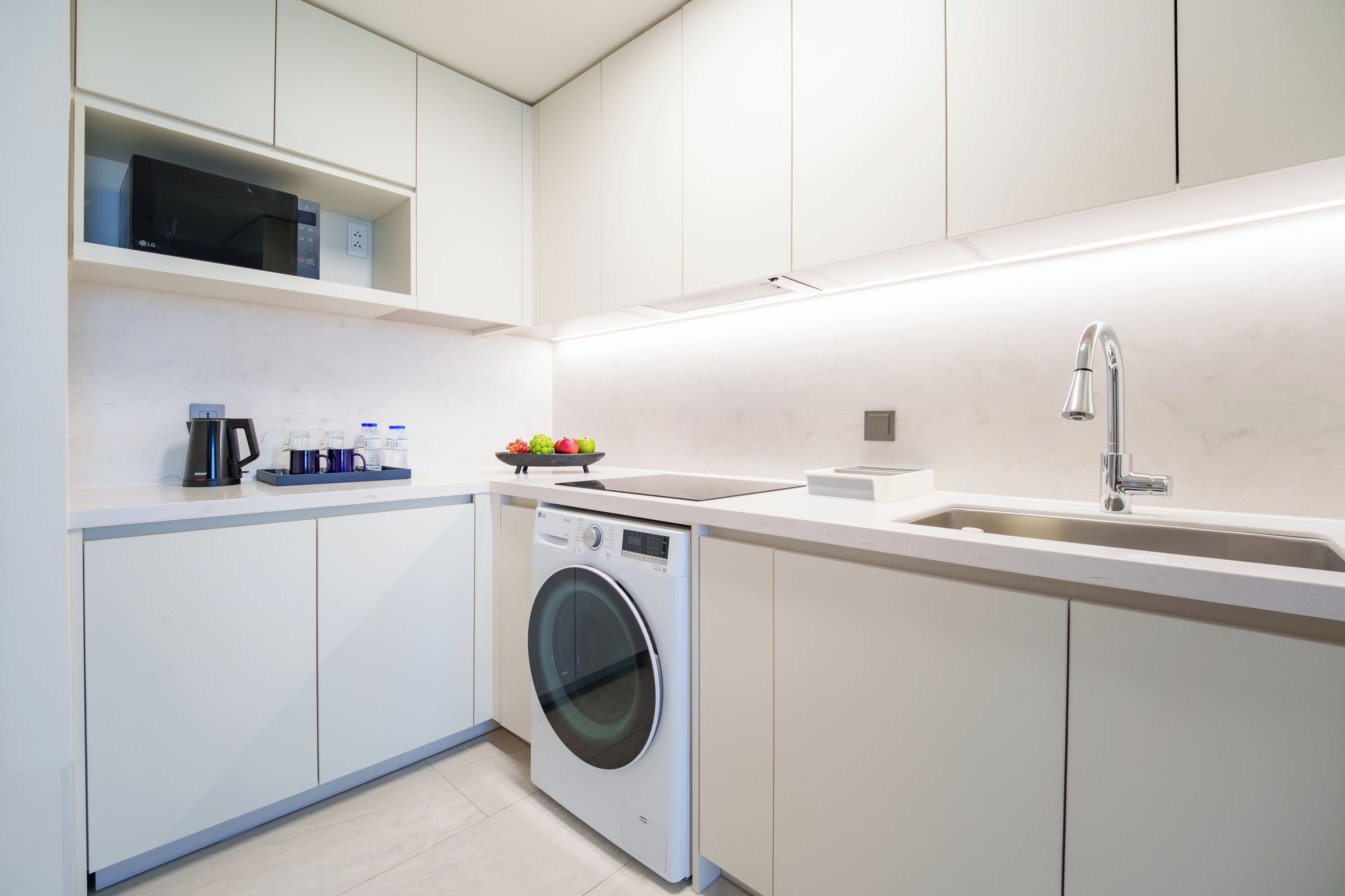 A modern kitchen with a built-in washing machine, a microwave, and a sink.