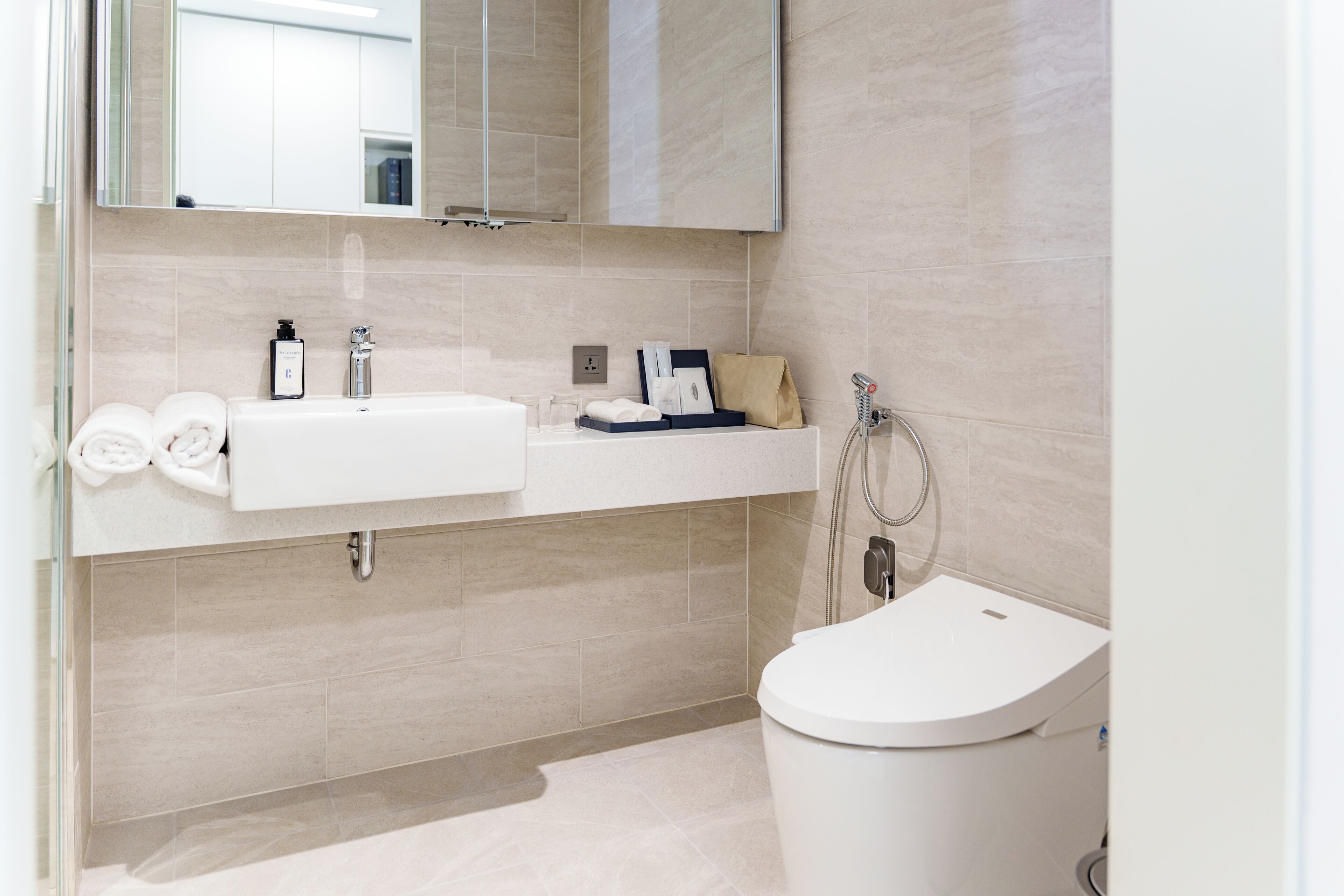 A modern bathroom with a white sink, mirror, and toilet.