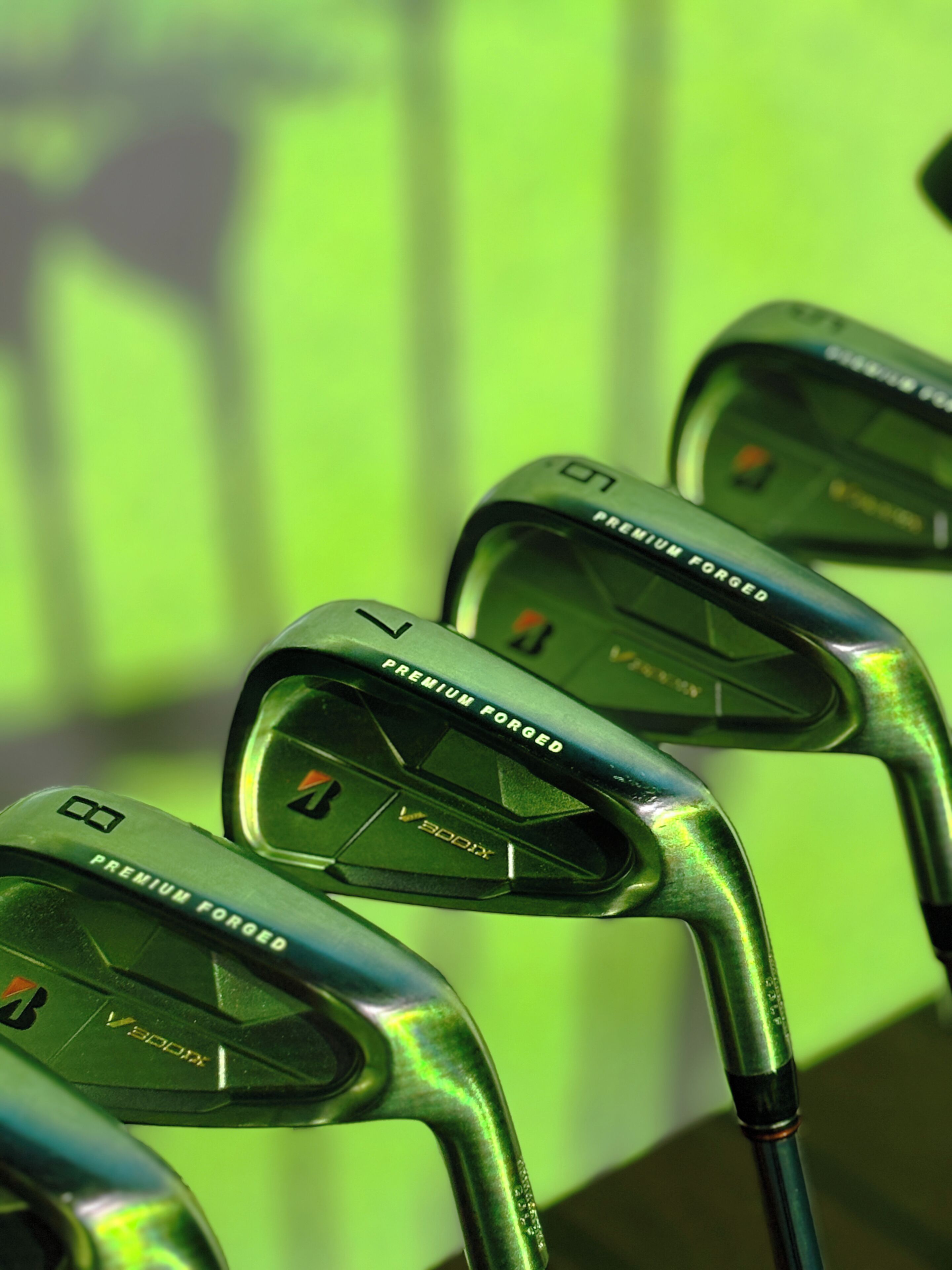 A close-up of golf clubs with 'PREMIUM FORGED' and 'V300X' visible on the heads.