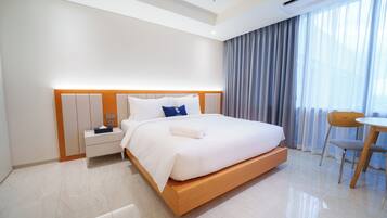 A modern hotel room with a large bed, bedside tables, a small desk, and a chair.