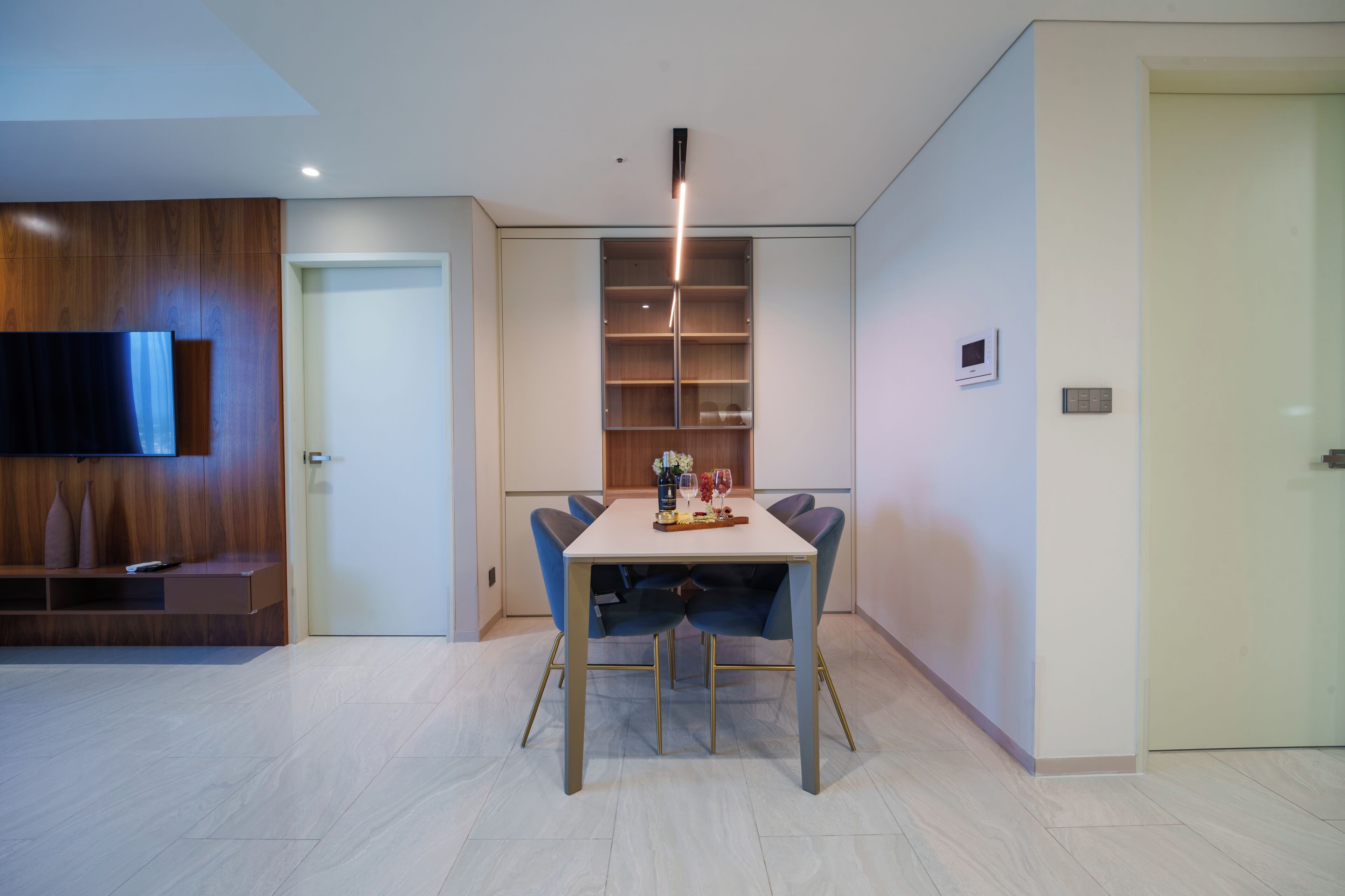 Un comedor moderno con una mesa, sillas, un televisor y una estantería empotrada.