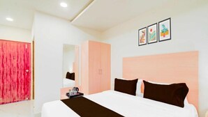 Una habitación de hotel con una cama grande, un armario, un espejo y una mesita con bandeja.