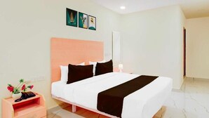 Una habitación de hotel con una cama, una mesita de noche, una lámpara y una pared decorada con tres cuadros.