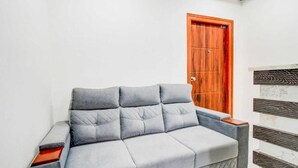 Un sofá gris con una mesita de madera, una puerta de madera y una pared blanca con un diseño de paneles de madera.