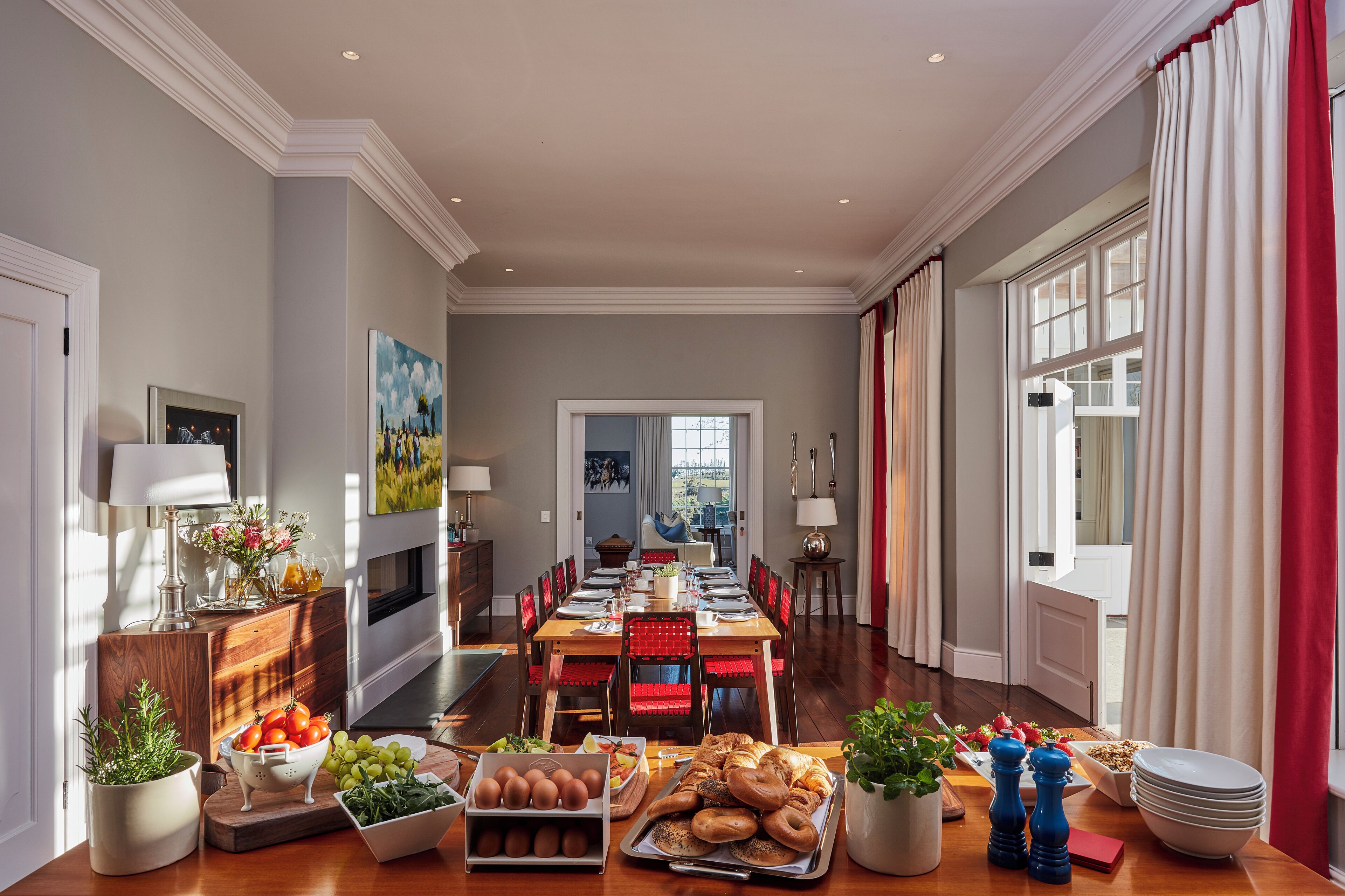 A spacious dining area with a long table set for a meal, surrounded by chairs.