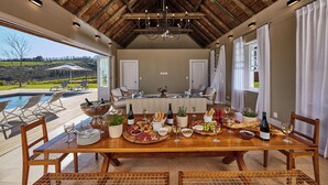 A dining area with a wooden table set for a meal, a pool, and a view of the outdoors. - Brookdale Estate - Manor House (Cape Town)