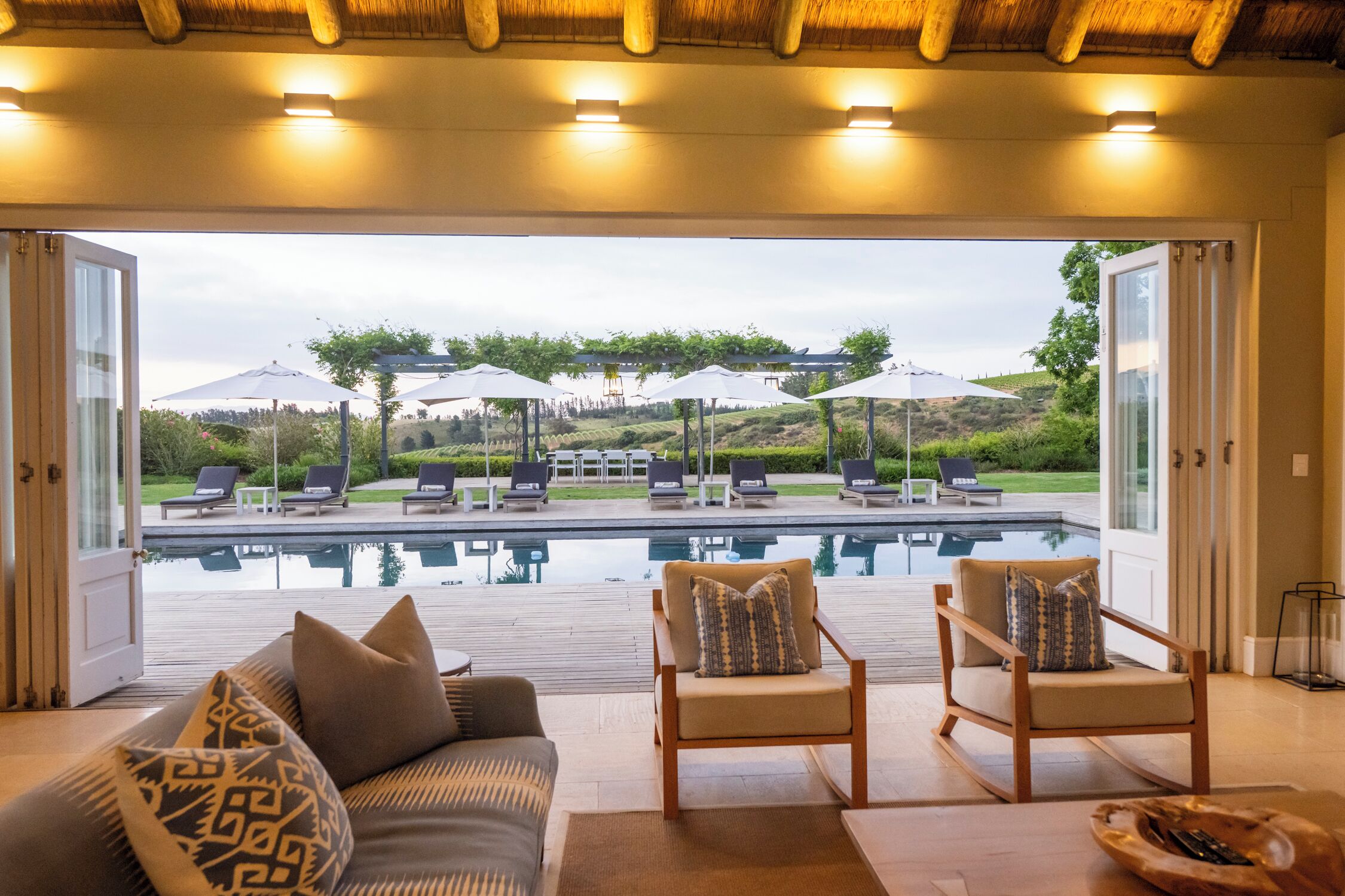 A modern indoor pool area with a view of an outdoor lounge area.