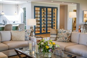 A modern living room with a sofa set, a coffee table with candles and a vase of flowers, and a bookshelf in the background. - Brookdale Estate - Manor House (Cape Town)