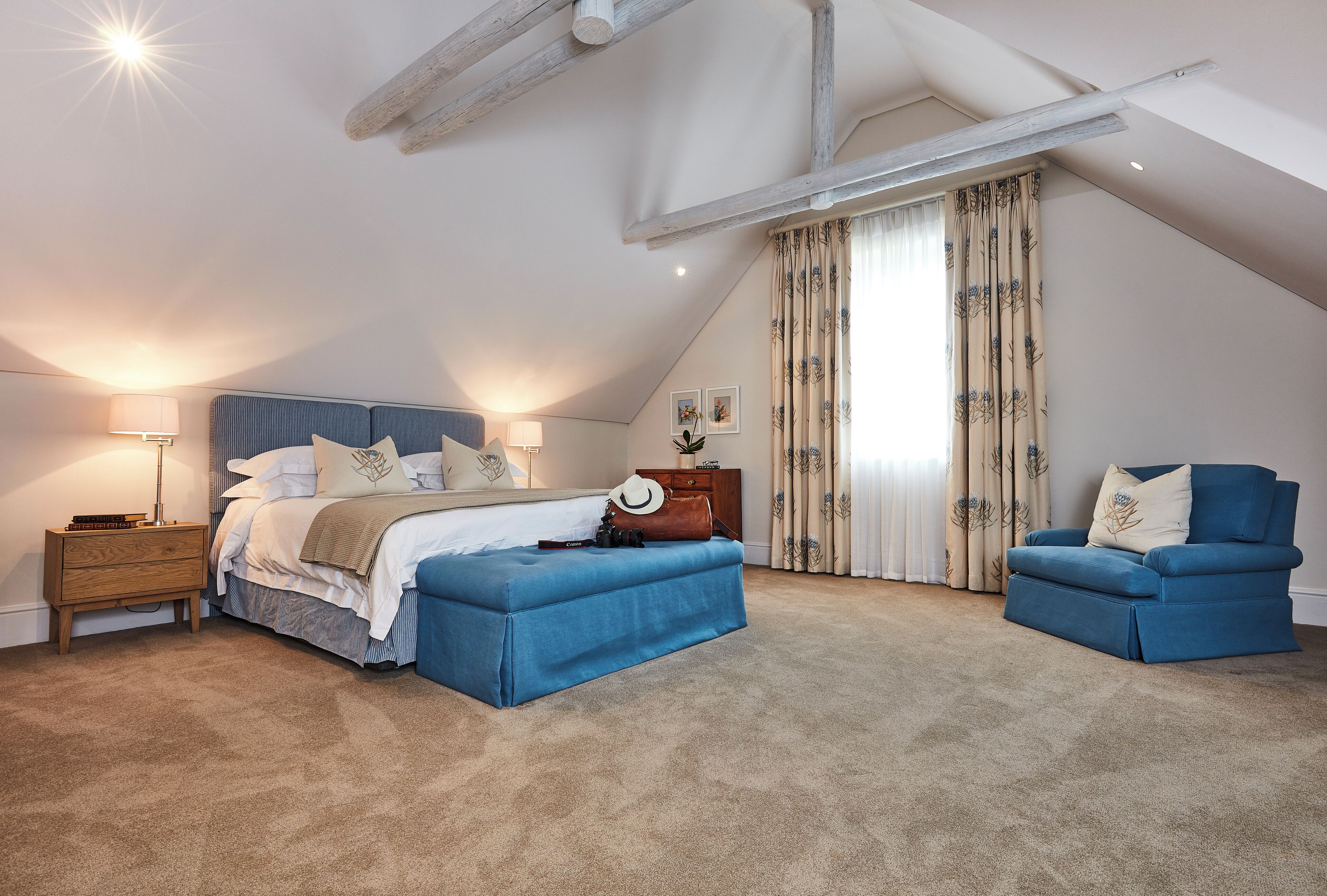 A bedroom with a bed, a blue armchair, a wooden nightstand, and a dresser.