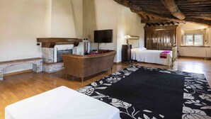 Ein Zimmer mit Holzboden, Fernseher, Bett, Sofa und Kamin.