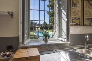 A kitchen with a large window overlooking a pool, a wooden box labeled 'SAN FELICE,' and a marble countertop.