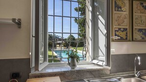 Eine Küche mit einem gro ßen Fenster mit Blick auf einen Pool, einer Holzschatulle mit dem Aufdruck 'SAN FELICE' und einer Marmorarbeitsplatte.