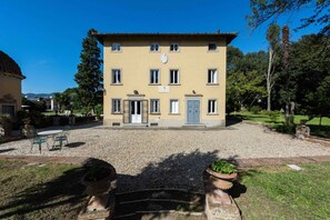 A two-story building with a symmetrical facade, a central entrance, and a gravel driveway.