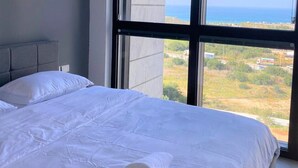 Un dormitorio con un amplio ventanal que ofrece vistas al mar y al paisaje distante.