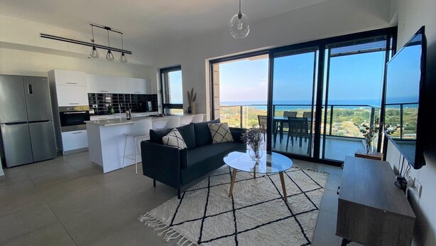 Un apartamento moderno con cocina, sala de estar y balcón con vistas al mar.