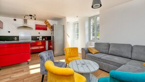 Eine moderne Küche mit roten Schränken, einem grauen Sofa und gelben Stühlen.