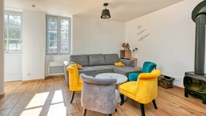 Ein modernes Wohnzimmer mit grauem Sofa, gelb-grauen Sesseln, einem runden Couchtisch und einem Kamin.