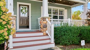 A house with a porch, stone steps, a wreath on the door, and a sign indicating a point of interest. - All In | Pool Access | Fire Pit | Game Room (South Haven)
