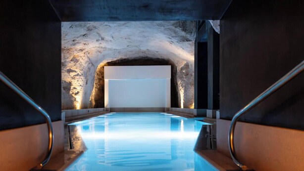 Ein Hallenbad mit einer Steinwand und einer großen weißen Leinwand am Ende.