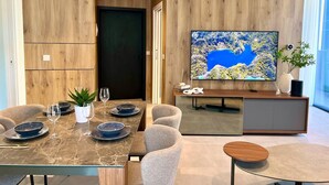 Ein modernes Wohnzimmer mit Essbereich, einem Flachbildfernseher und einer Wand als Holzdekor.