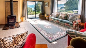 Een gezellige woonkamer met een open haard, een bank en een groot raam met een prachtig uitzicht.