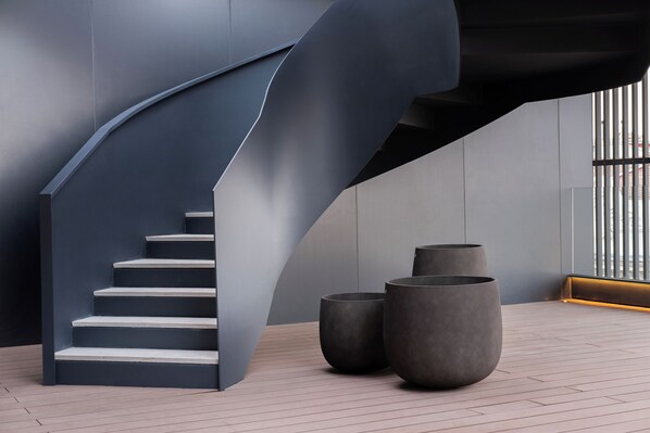 A modern staircase with a curved design, large planters, and a view of the outside. - Eurostars Valladolid (Valladolid)