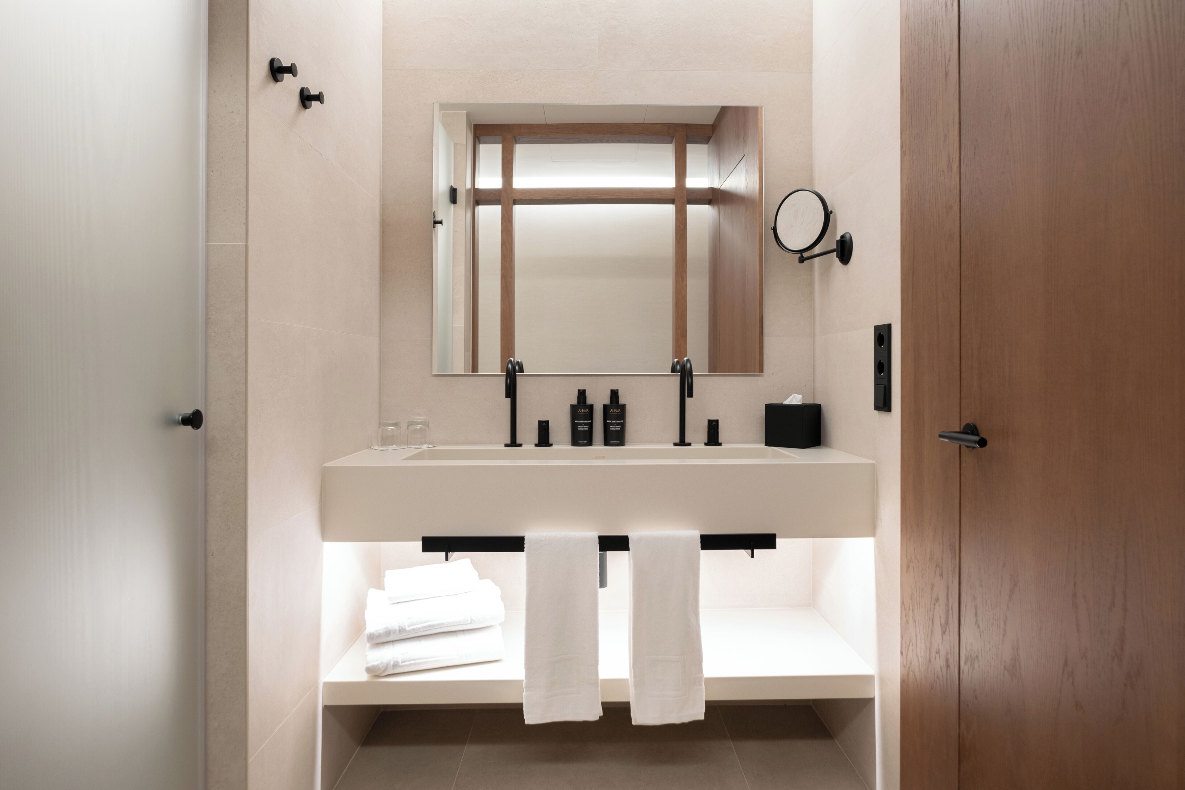 Un baño moderno con un espejo grande, un lavamanos y un perchero para toallas.