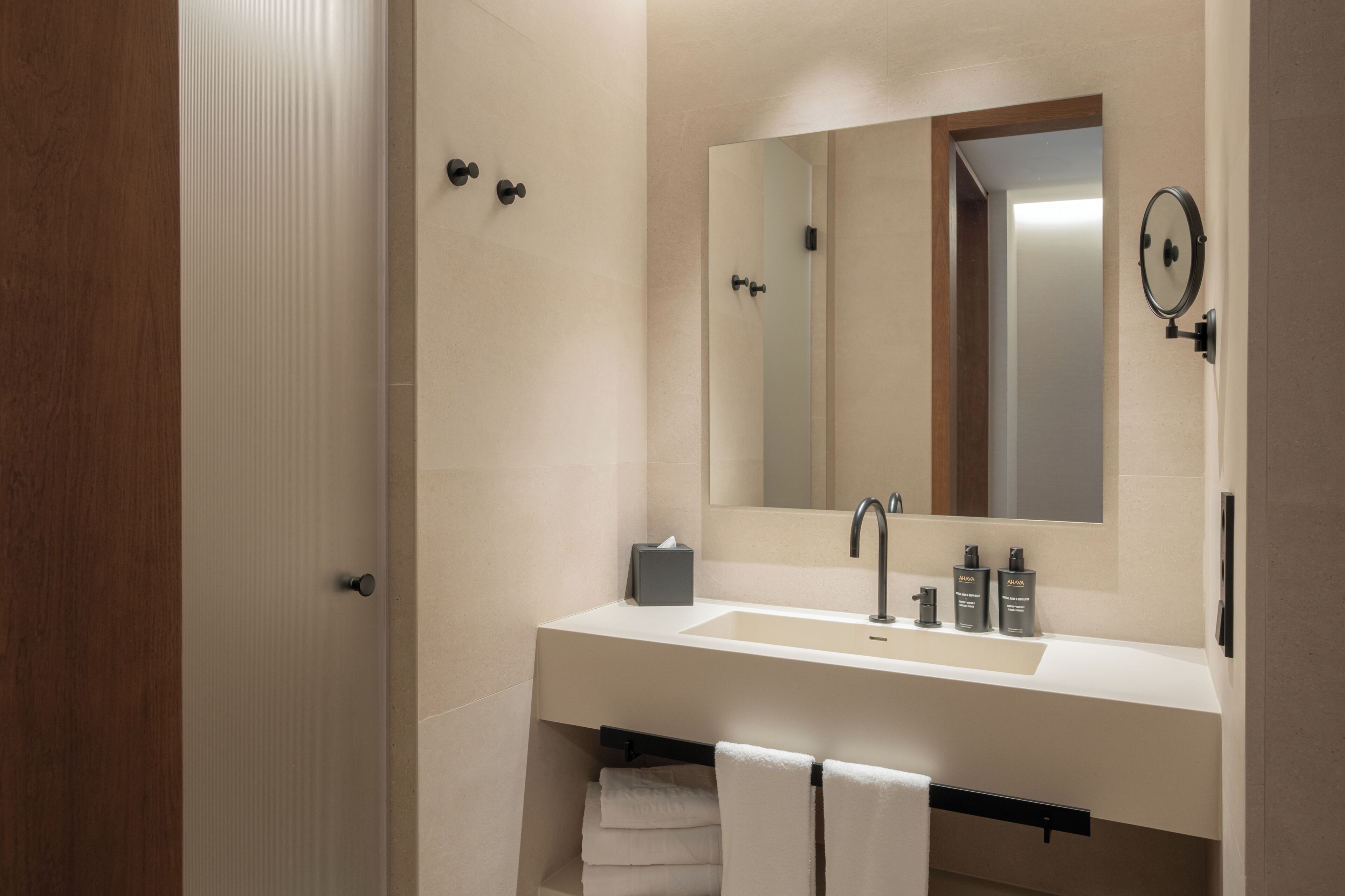 Ein modernes Badezimmer mit Waschbecken, Spiegel, Handtuchhalter und einer Tür.