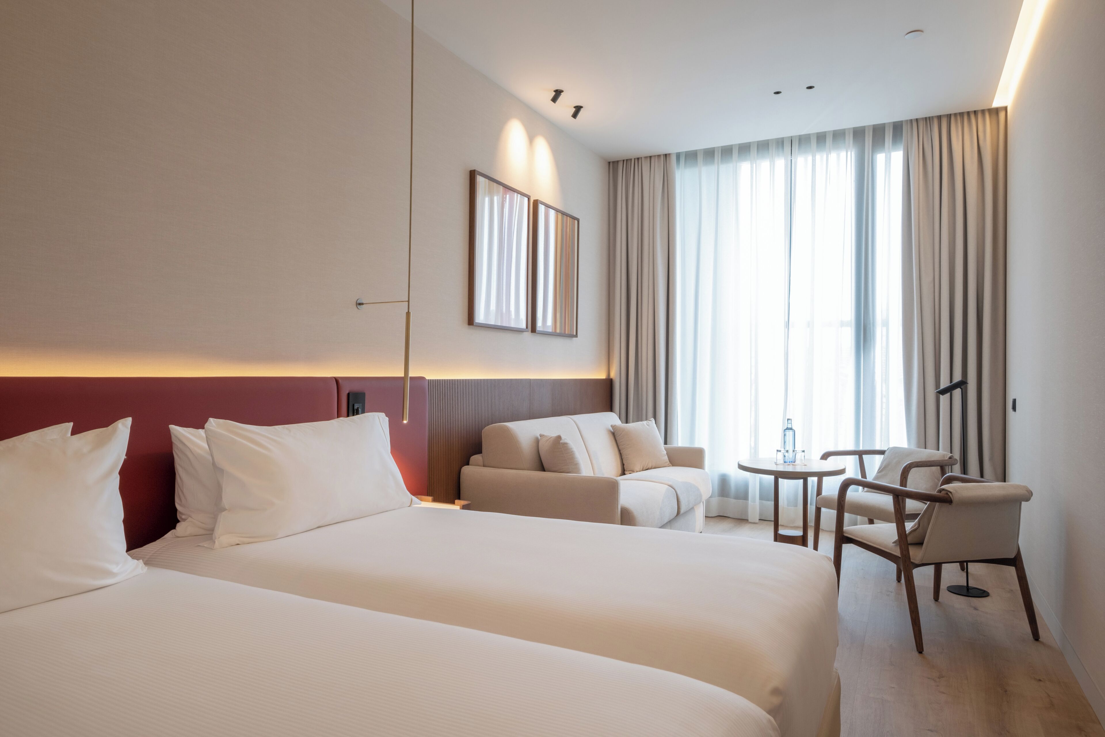 Una habitación de hotel con dos camas, un sofá, una mesita y una silla.