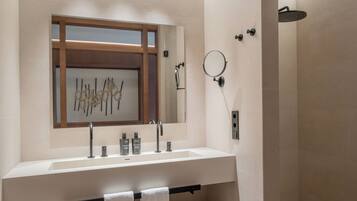 Un baño moderno con un lavamanos grande, espejo y ducha.