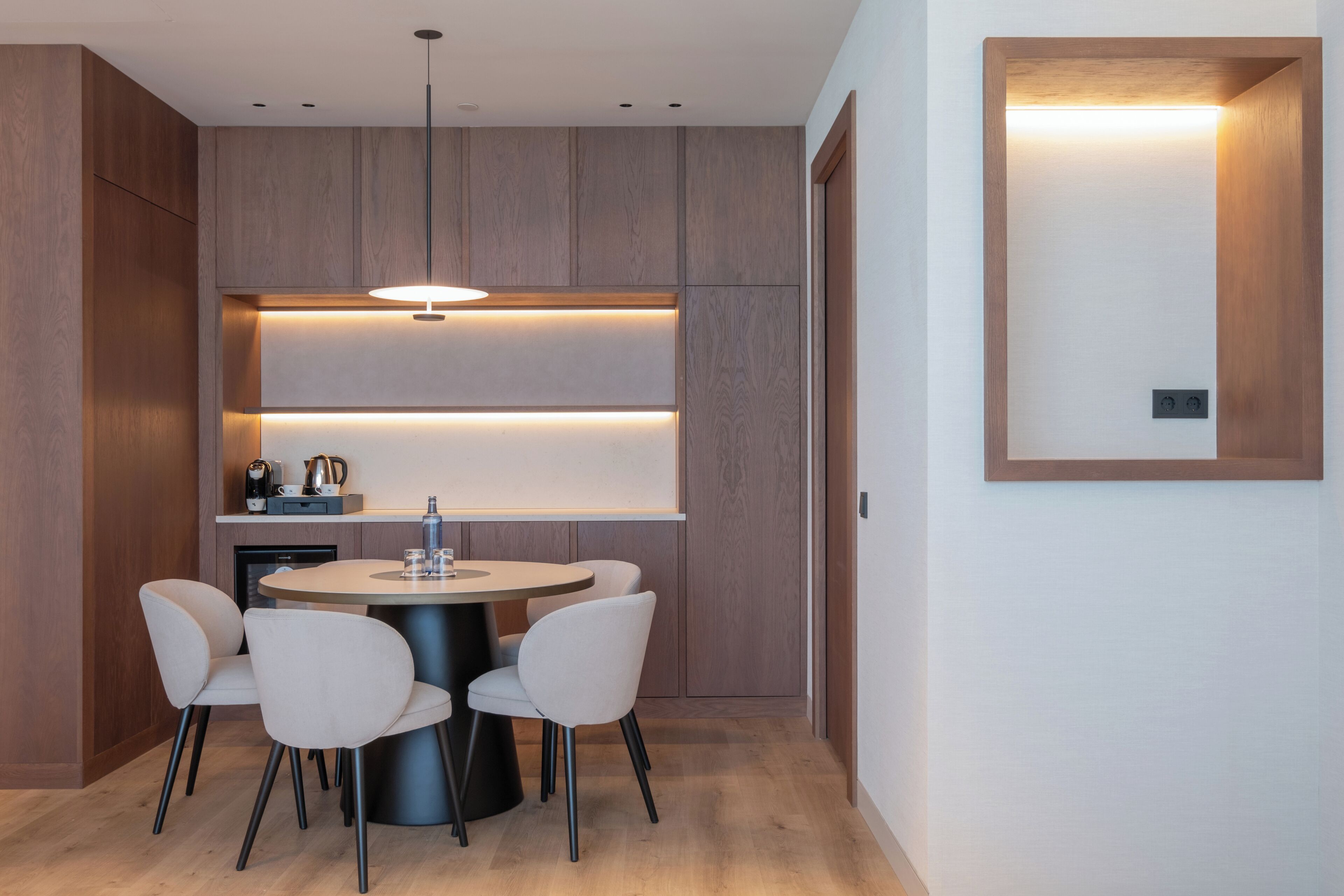 Una cocina moderna con armarios de madera, una mesa redonda y cuatro sillas.