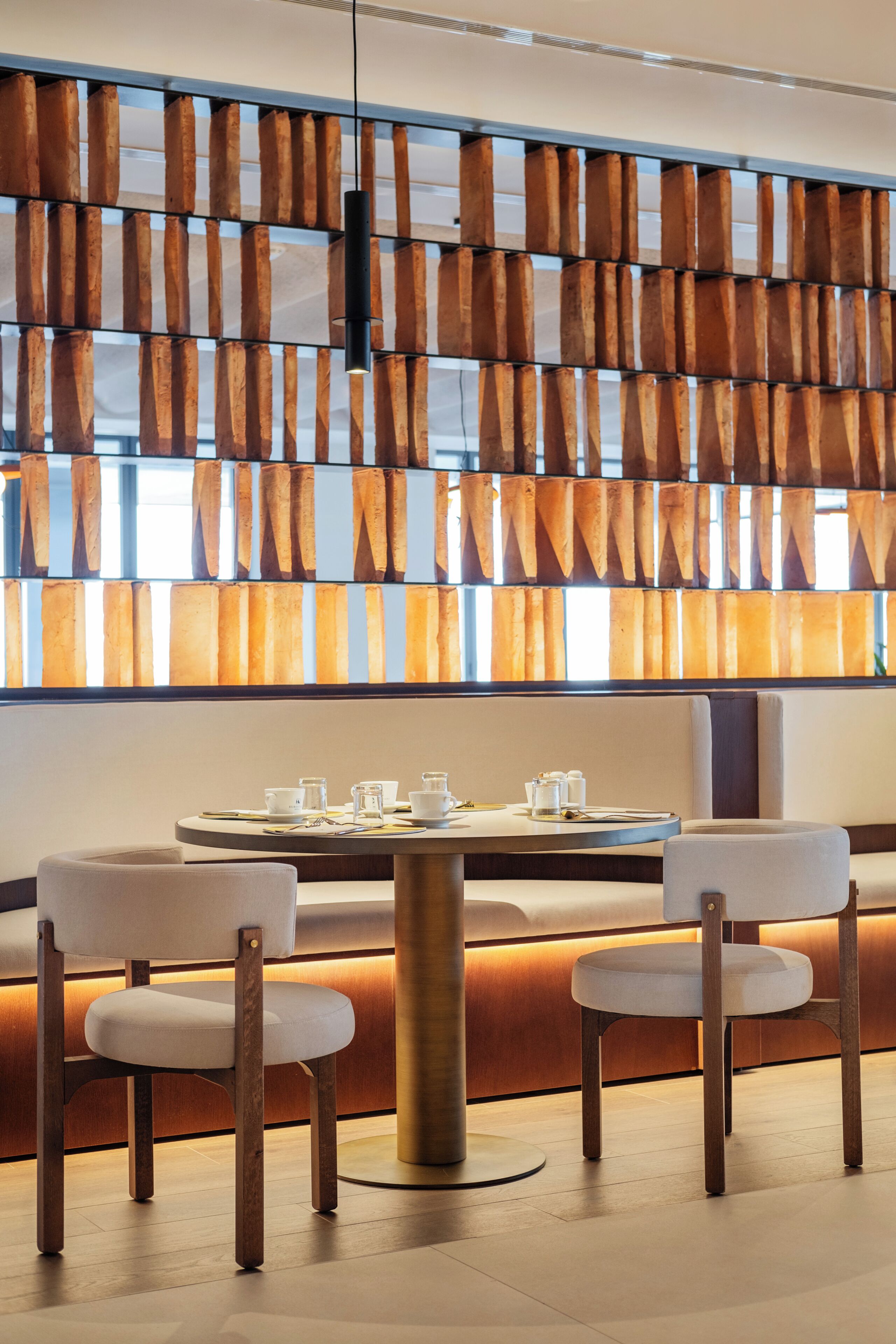A modern interior with a wooden wall panel, a round table with chairs, and a seating area.