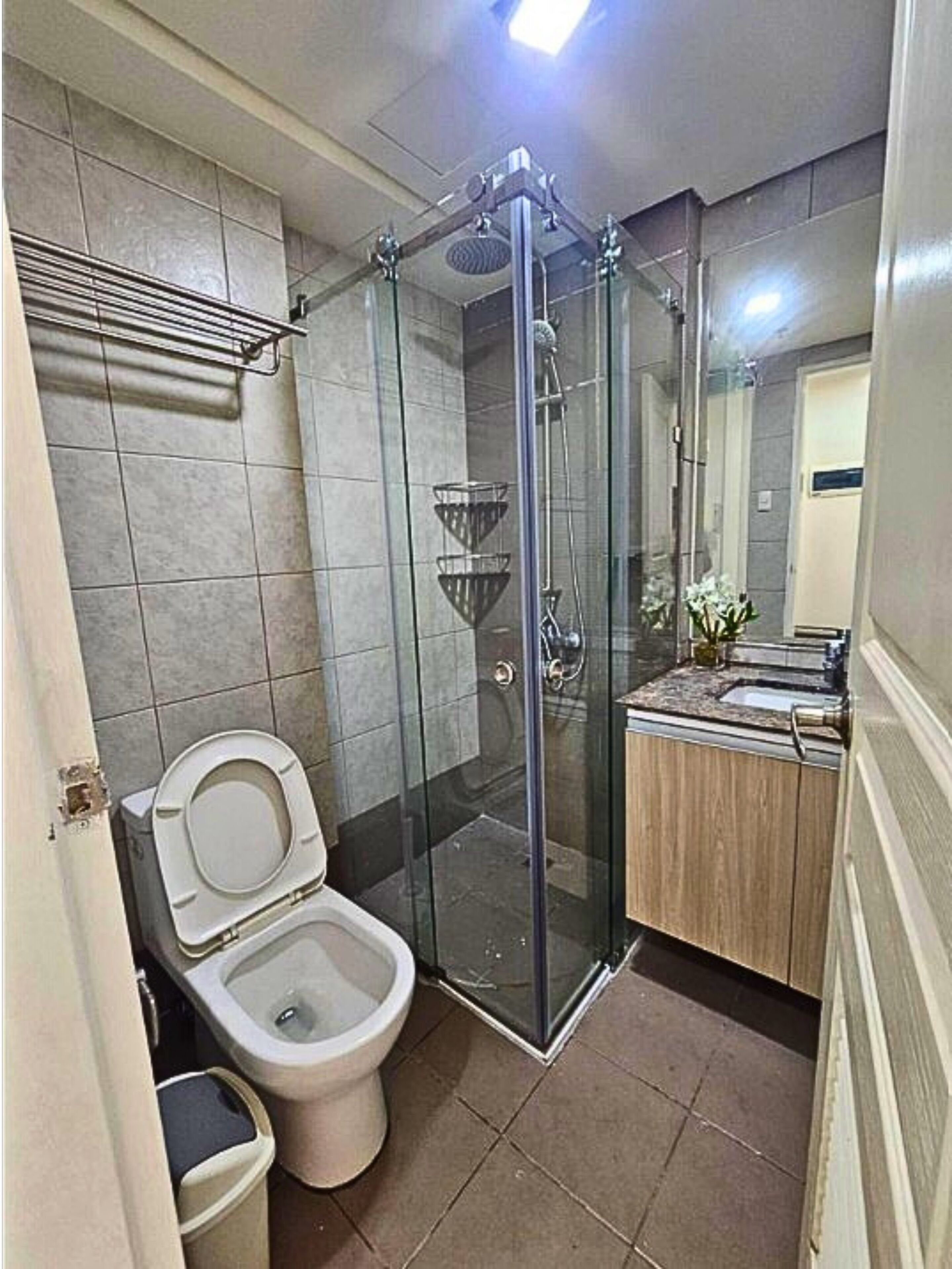 A bathroom with a glass-enclosed shower, a toilet, and a sink with a mirror.