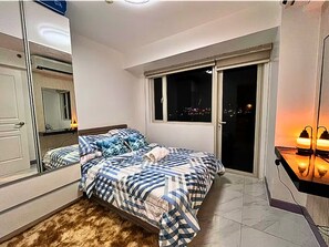 A bedroom with a bed, a mirror, a window, and a nightstand with a lamp. - Stay Beside Mall of Asia Walk & Explore (Parañaque)