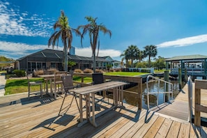 A wooden deck with outdoor furniture, a covered seating area, and a water feature. - Reel Relaxed | Team Joseph Ellen (Jacksonville Beach)