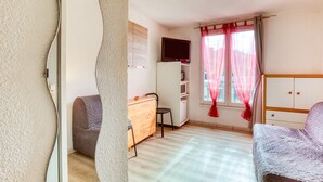 Una habitación con cama, escritorio, silla, televisor y ventana con cortinas.