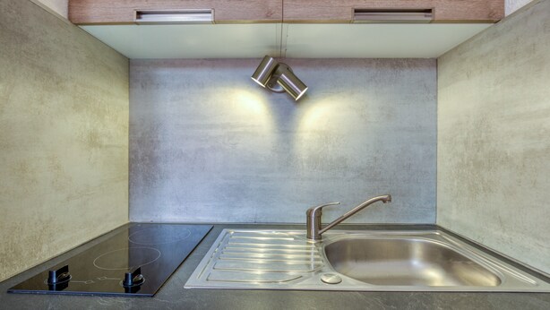Una cocina moderna con un lavamanos de acero inoxidable, una estufa integrada y armarios de madera arriba.