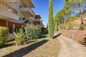 A residential building with multiple balconies, a pathway, and surrounding greenery.
