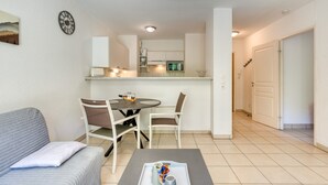 Una sala de estar moderna con un sofá, sillones, una mesa de centro y un comedor con una mesa y sillas.
