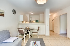 A modern living room with a sofa, chairs, a coffee table, and a dining area with a table and chairs.