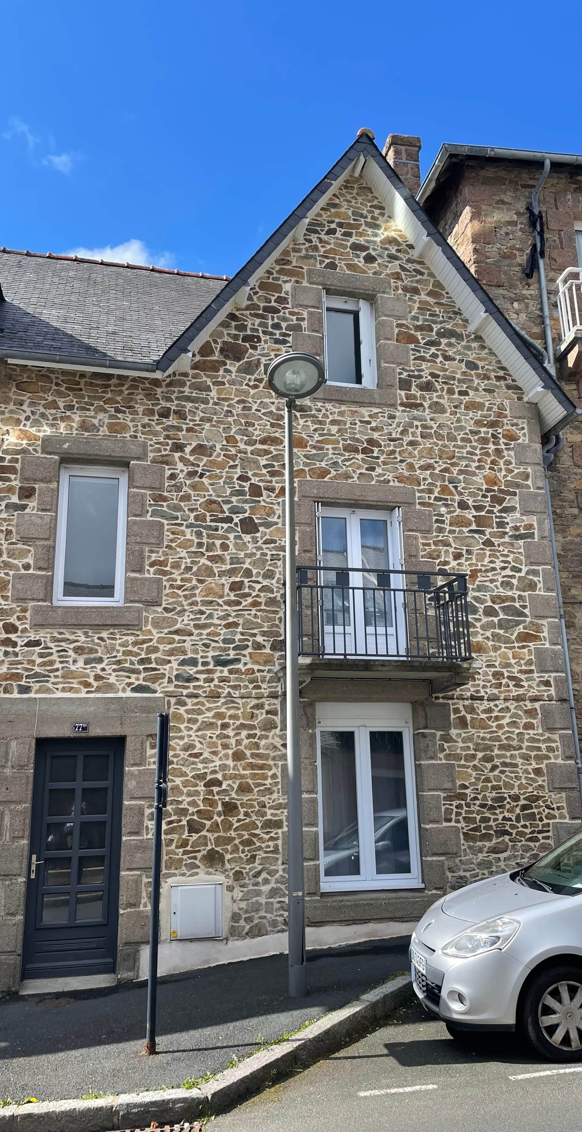 Ein Gebäude aus Stein mit Balkon, einer Tür und einem Fenster.