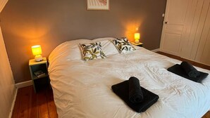 A bedroom with a large bed, two bedside lamps, a framed picture on the wall, and a door to the right. - Ker Levenez - Stone house Perros-Guirec (Perros-Guirec)