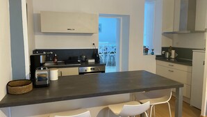 A modern kitchen with a central island, white bar stools, and a view to a balcony. - Ker Levenez - Stone house Perros-Guirec (Perros-Guirec)